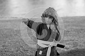 Kid boy practicing karate outdoor. Sport karate kids. Little boy wearing kimono doing karate in park. Child training box