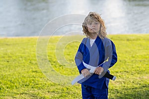 Kid boy practicing martial arts outdoor. Sport martial arts kids. Little boy wearing kimono doing karate in park. Child