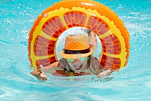 Kid boy relaxing in pool swim on float ring. Child swimming in water pool. Summer kids activity, watersports. Fashion