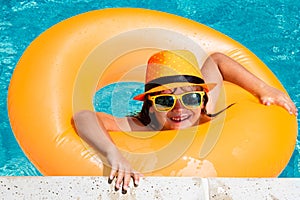 Kid boy relaxing in pool swim on float ring. Child swimming in water pool. Summer kids activity, watersports. Vacations