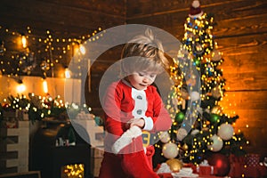 Kid boy santa hold christmas gift red sock. Childhood moments. Christmas stocking concept. Child cheerful face got gift