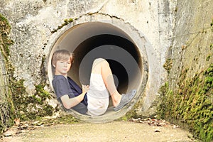 Kid - boy sitting in sluice-way