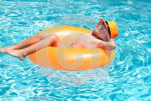 Kid boy splashing in swimming pool having fun, leisure activity. Child boy in swimming pool with inflatable ring. Kids
