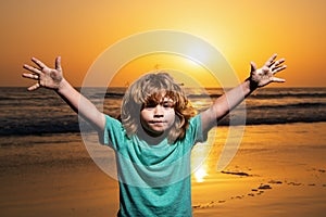 Kid boy on sunset beach, raised hands. Amazed surprised kids emotions.