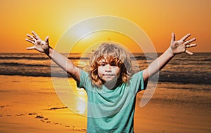 Kid boy on sunset beach, raised hands. Amazed surprised kids emotions.