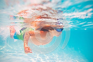 Kid boy swim underwater in summer pool. Summer kids vacation concept. Funny kids face underwater. Child splashing in