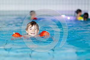 Kid boy with swimmies learning to swim in an indoor pool