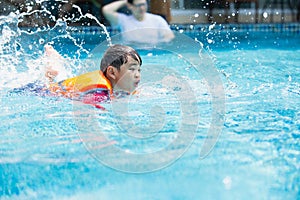 Kid boy swimming pool exercise in holiday activities.