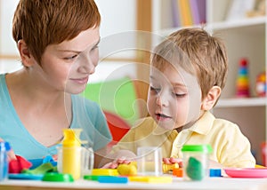 Kid boy with teacher play clay at home, kindergarten, daycare center or playschool photo
