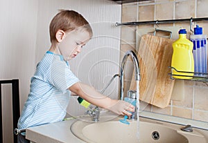 Kid boy washing dish on kitchen