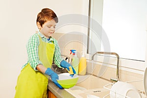 Kid boy washing dishes under running water