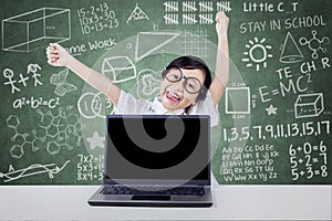 Kid celebrate her achievement with laptop in class