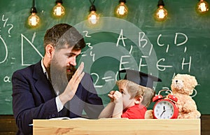 Kid cheerful distracting while studying, attention deficit. Teacher and pupil in mortarboard, chalkboard on background