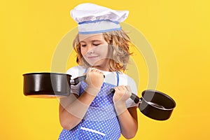 Kid chef cook with cooking pot stockpot. Child in cook uniform. Chef kid isolated on yellow background. Cute child to be photo