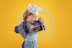 Kid chef cook with cooking pot stockpot. Cooking children. Chef kid boy in form of cook. Child boy with apron and chef photo