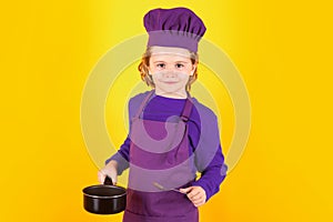 Kid chef cook with cooking pot stockpot. Excited chef cook. Child wearing cooker uniform and chef hat preparing food