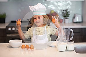 Kid chef cook with eggs at kitchen. Child chef cook prepares food at kitchen. Kids cooking. Teen boy with apron and chef