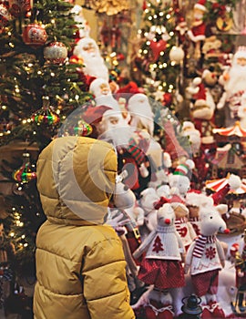 Kid child boy standing in front of store shopwindow with New year Christmas decorations of store front, showcase, glass case,