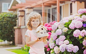 Kid child dreaming of new home. Happy boy holding dream house in their hands, real estate and home insurance concept.