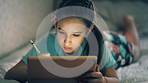 Kid child girl holding digital tablet. Teenager learning at home. Child Writing Homework for School, Girl Studying at