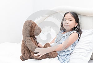 Kid or child playing doctor with stethoscope and teddy bear