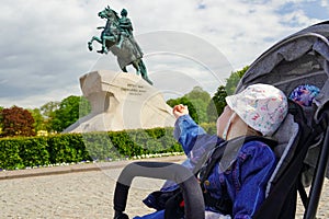 Kid child in Saint-Petersburg near Bronze Horseman statue at summer