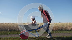 Kid children play with a garden trolley car ride on wheelbarrow. happy family farming dream concept. happy family