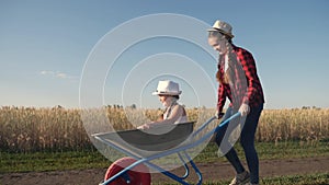 Kid children play with a garden trolley car ride on wheelbarrow. happy family farming dream concept. happy family