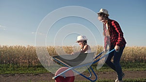 kid children play with a garden trolley car ride on wheelbarrow. happy family farming dream concept. happy family