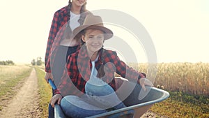 Kid children sisters play with a garden lifestyle trolley car ride on wheelbarrow. little girl child in hat happy family