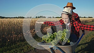 Kid children sisters play with a garden trolley car ride on wheelbarrow. little girl child in hat happy family