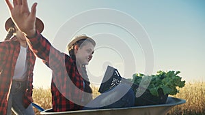 kid children sisters play with a garden trolley car ride on wheelbarrow. little girl child in hat happy family