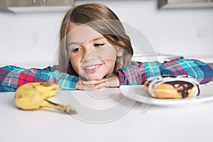 Kid choosing between healthy vegetables and tasty sweets