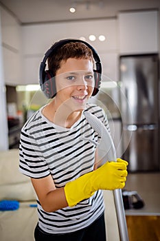 Kid cleaning the floor and listening to the music. He is doing his chore and he is dancing