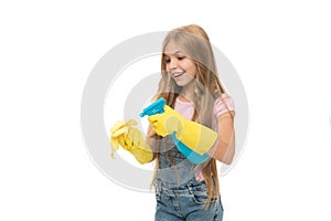 Kid cleaning at home. Mist sprayer helpful for wiping dust. Girl yellow rubber protective gloves ready for cleaning copy