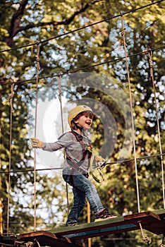 Kid climbing trees in park. Beautiful little child climbing and having fun in adventure Park. Safe Climbing extreme