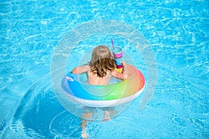 Kid with colorful swim ring in swimming pool on summer day. Water toys and floats for child. Healthy sport for children