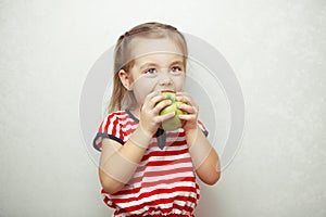 Kid with cute hairstyle holding and eating green apple