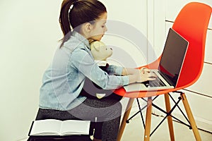 Kid or cutegirl hugging teddy bear and typing on laptop