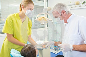 Kid in dental chair with dentist after repairing teeth