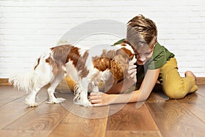 Kid with dog indoor. Teen boy is training her puppy at home. Happy boy playing hugging his funny pet puppy dog domestic