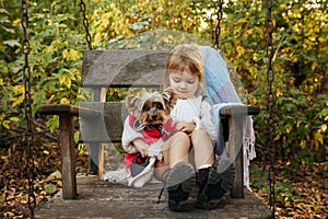 Kid with dog are sitting in big wooden chair