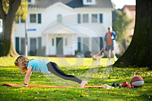 Kid doing push-ups sport exercises in park. Sport, healhty lifestyle, training, active leisure outdoor. Kid pushing up