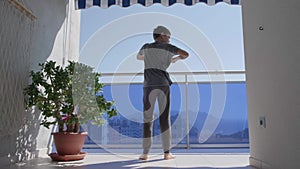 Kid doing sport exercises, crouching on the balcony. Sport, healhty lifestyle, active leisure at home