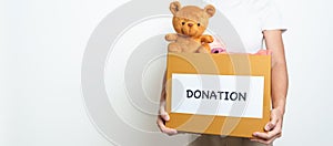 Kid Donation, Charity, Volunteer, Giving and Delivery Concept. Hand holding Bear doll and Clothes into Donation box at home for