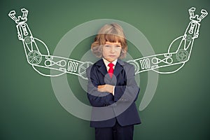 Kid with drawn robot hands against blackboard