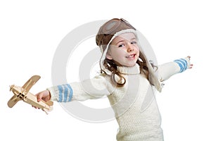 Kid dressed as pilot and playing with wooden air plane toy isolat