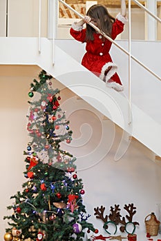 Kid dressed like santa going downstairs for christmas gifts