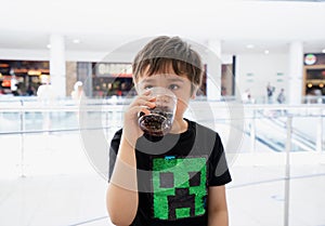 Kid drinking cold soda, Happy Child sitting in cafe drinking soft drink from glass, sitting in cafe drinking soda or soft drink