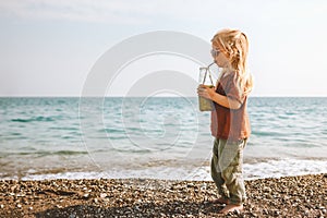 Kid drinking smoothie on sea beach child with glass bottle healthy lifestyle vegan food detox beverage